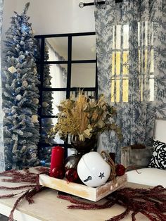 a living room decorated for christmas with blue and white decorations on the coffee table, red candles, and tree branches