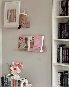 there are books on the wall and two shelves with flowers in vases next to them