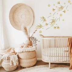 a baby crib next to a white wall with flowers on it and a wicker basket in the foreground