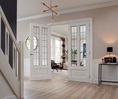 an open door leading to a living room with white walls and wood floors, along with a staircase that leads up to the second floor