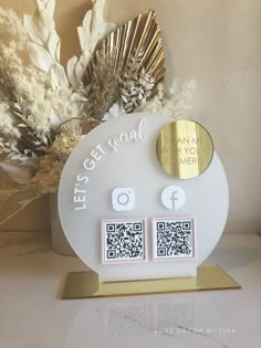 a white and gold clock sitting on top of a table next to dried plants in vases