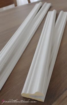 three white plastic tubes sitting on top of a wooden table next to a window sill