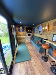 the inside of a home with wood paneling and blue couches, bar stools