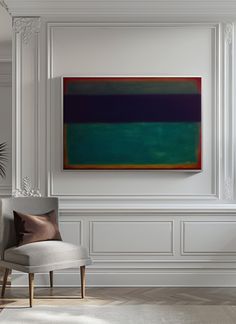 an abstract painting hangs on the wall above a chair in a room with white walls