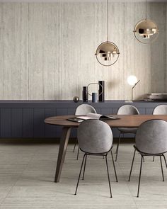 a modern dining room with grey chairs and an oval wooden table surrounded by round pendant lights