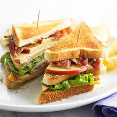 a sandwich cut in half sitting on top of a white plate next to some chips