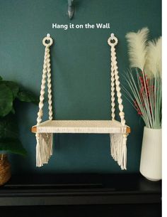 a white macrame hanging on the wall next to a potted plant