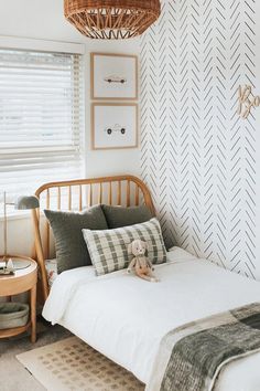 a bedroom with white walls and black and white patterned wallpaper, a wicker basket hanging over the bed