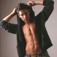 a shirtless man with no shirt on posing for the camera, wearing jeans and holding his jacket over his head