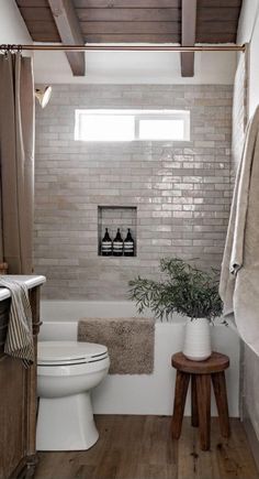 a white toilet sitting next to a bath tub in a bathroom under a wooden ceiling