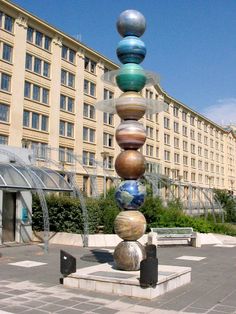 a sculpture in front of a building with many balls on it's top and bottom