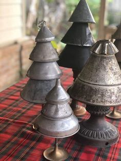 four metal christmas trees sitting on top of a red tablecloth covered table with windows in the background