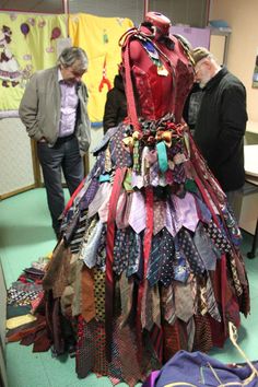 there is a dress made out of ties on display in the room with people looking at it