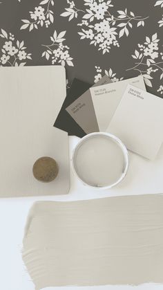 some white paint is sitting on a table next to a brown and white flowered wallpaper