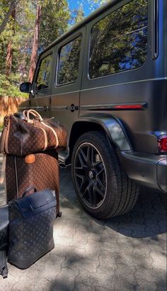 two suitcases are sitting next to a parked car with a bag on the ground