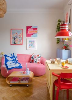 a living room with pink couches and colorful art on the wall above it's coffee table