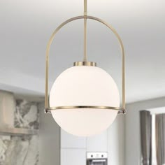 a light fixture hanging from the ceiling in a kitchen with marble counter tops and cabinets