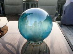 a blue glass ball sitting on top of a wooden table next to a white couch