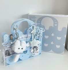 a white teddy bear in a blue bag with keychain and other items next to it