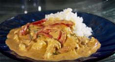 a blue plate topped with rice and meat covered in sauce