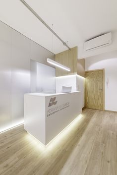 an office with white walls and wood flooring is lit up by led lighting on the front desk