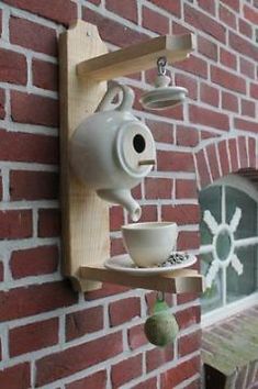 a brick wall with a teapot and cup on it hanging from the side of a building