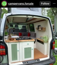 the back end of a camper van with its door open and shelves on it