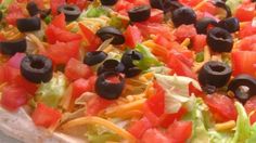 a pizza topped with lettuce, tomatoes and olives on top of it