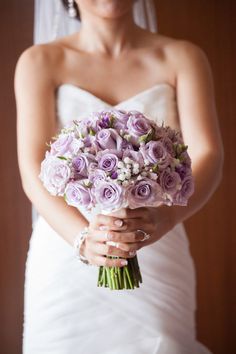 a bride holding a bouquet of purple roses