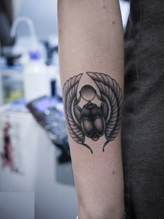 a woman's arm with a tattoo on it that has an insect in the middle