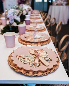 the table is set with pink and gold plates, cups, and napkins on it