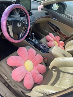 a pink flower sitting in the center of a car with steering wheel and dash board