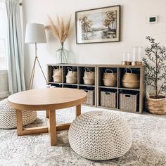 a living room filled with lots of furniture and baskets on top of the floor in front of a window