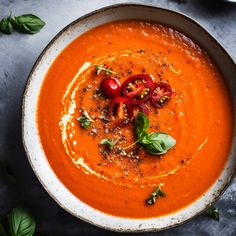 a white bowl filled with tomato soup and garnished with basil