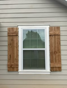 an open window on the side of a house with wooden shutters and white trim