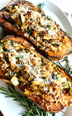 two stuffed sweet potatoes topped with cheese and herbs on a white plate, ready to be eaten