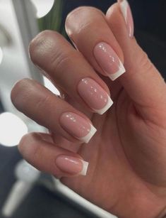 a woman's hand with french manies and white tips on her nails, in front of a mirror