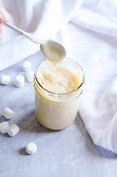 someone is spooning sugar into a jar filled with marshmallows