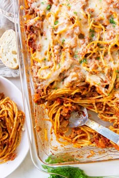 a casserole dish with meat and cheese on the side, next to bread