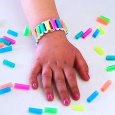 a child's hand with multicolored bracelets on it and scattered confetti