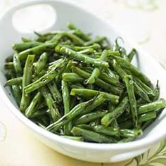 a white bowl filled with green beans on top of a table