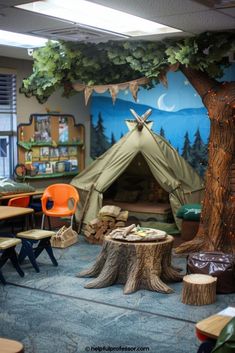 a classroom with tables, chairs and a tent in the middle is decorated with tree stumps