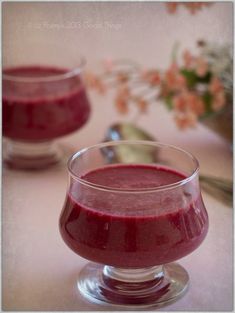 two glasses filled with red liquid sitting on top of a table