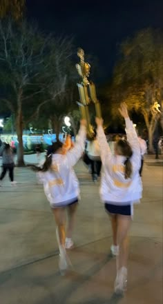 two cheerleaders holding up a trophy in the air