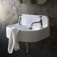 a white sink sitting under a bathroom mirror next to a wall mounted faucet