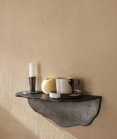 a shelf with two cups and saucers on it, next to a candle holder