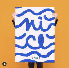 a person holding up a blue and white poster with the words nice written on it