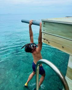 a man standing in the water holding onto a pole with his head above the water