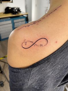 a woman with a tattoo on her shoulder that says love and an infinite sign in cursive writing