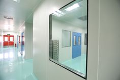 an empty hallway with blue and red doors on the walls, and a mirror in the middle